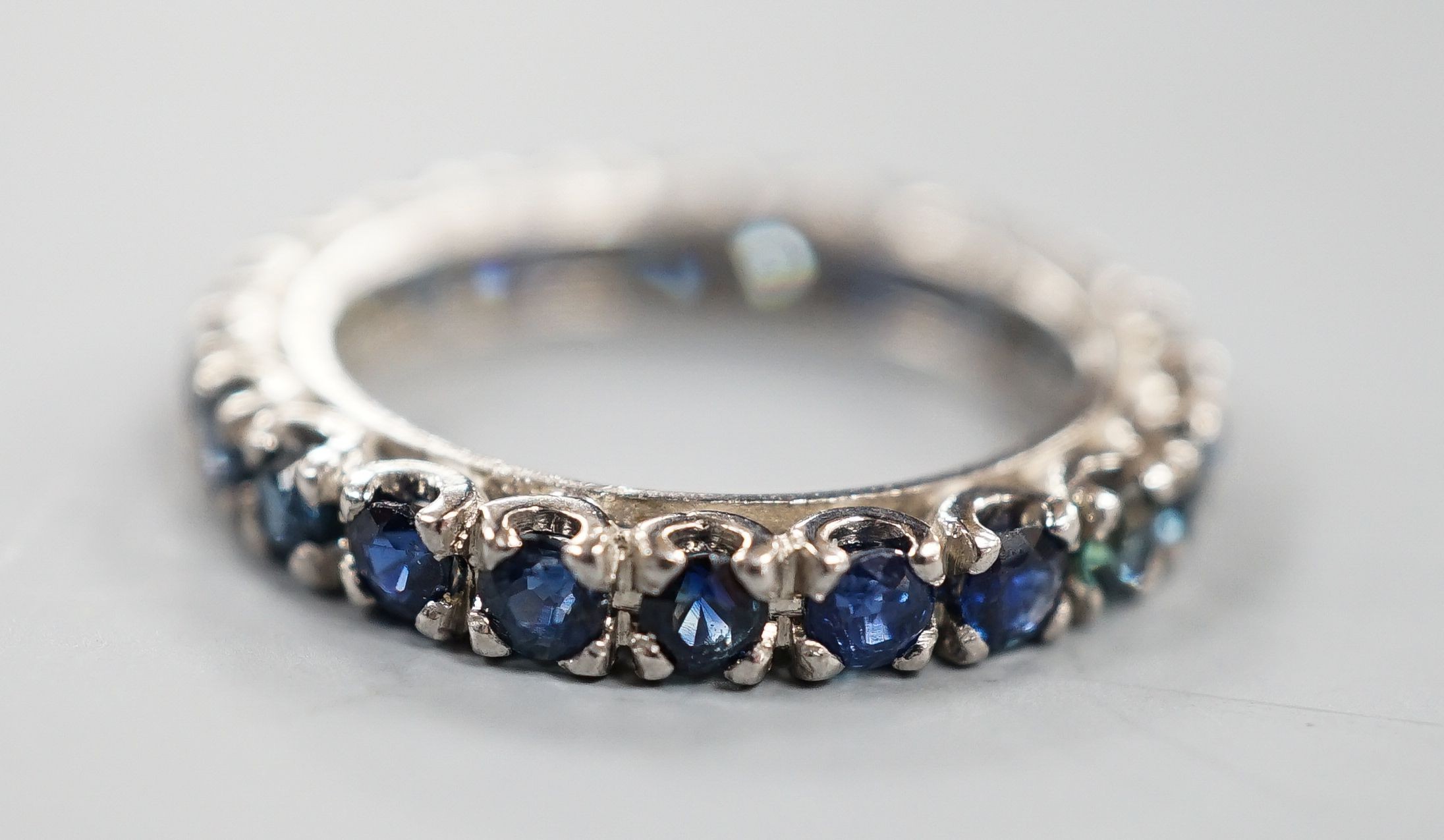 A white metal and sapphire set full eternity ring, size L, gross weight 3.4 grams.